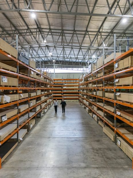 Interior of a commercial workshop featuring overhead gantry cranes, heavy machinery and industrial vehicles under a reinforced roof.