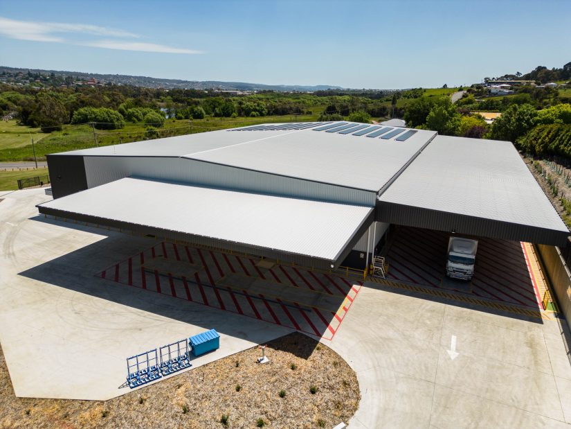 Modern warehouse construction featuring wide truck access bays and sustainable roofing design.