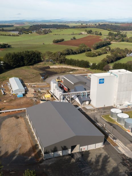 An aerial view of a farm in Tasmania featuring multiple agricultural storage sheds and processing buildings surrounded by rolling green fields. An example of comprehensive farm storage infrastructure.