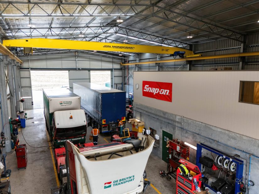 Workshop facility for heavy vehicle servicing with overhead cranes, branded workstations and industrial-grade roofing.